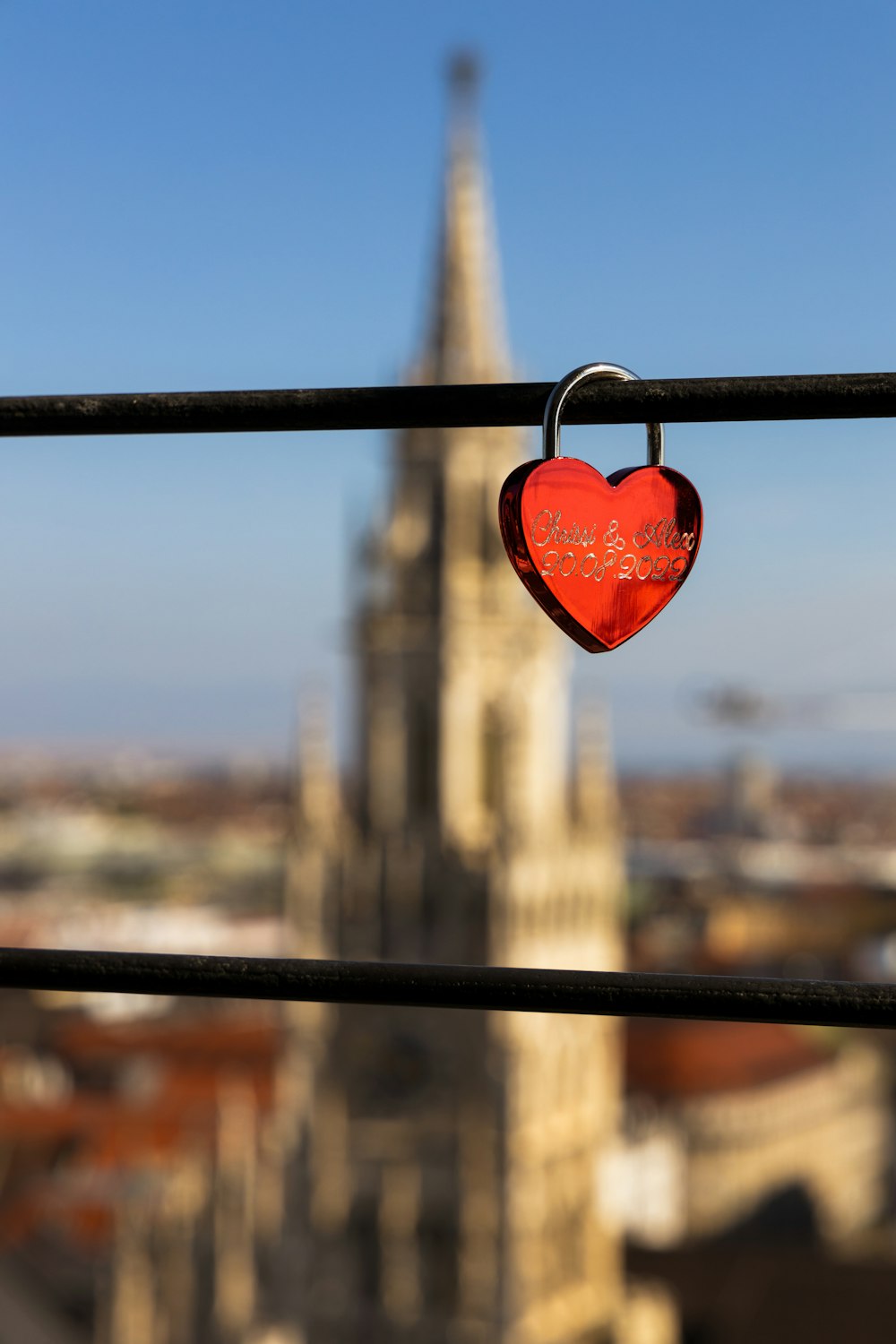 a red bell from a metal pole with a building in the background