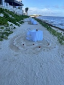A beautifully set table for a destination wedding on the white sands of a tropical beach at dusk.