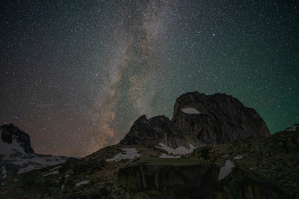 a mountain with snow and stars in the sky