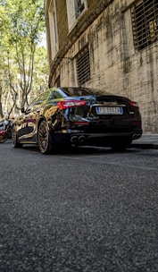 A sleek black sedan parked on a sunlit street in Accra, showcasing its polished finish.