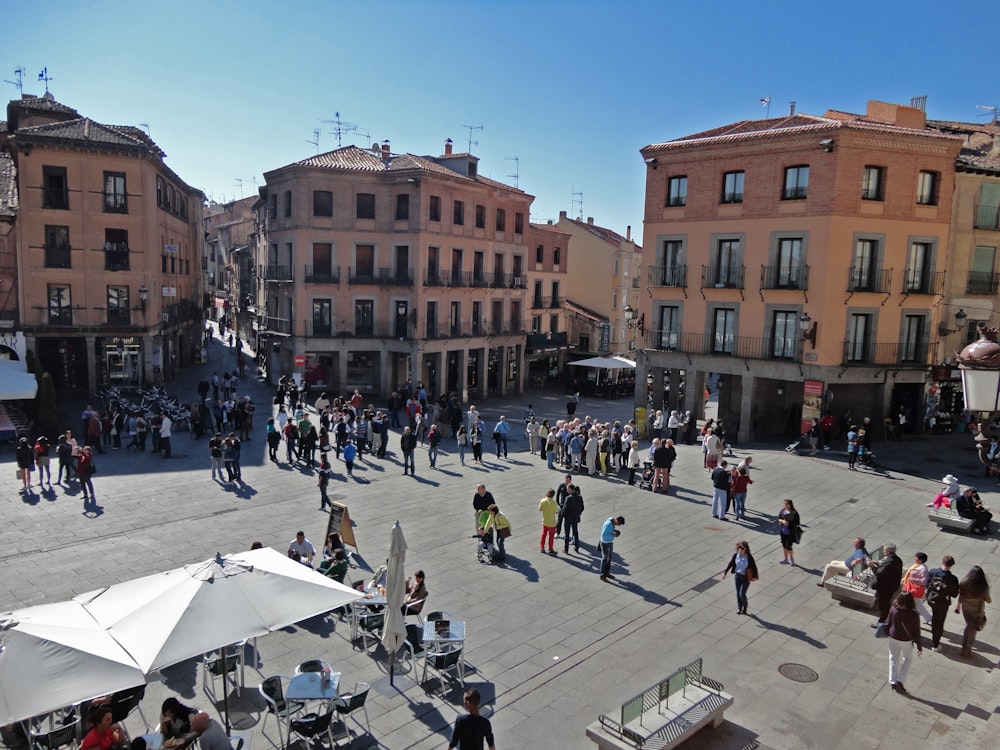 a group of people walking around a courtyard with buildings in the background