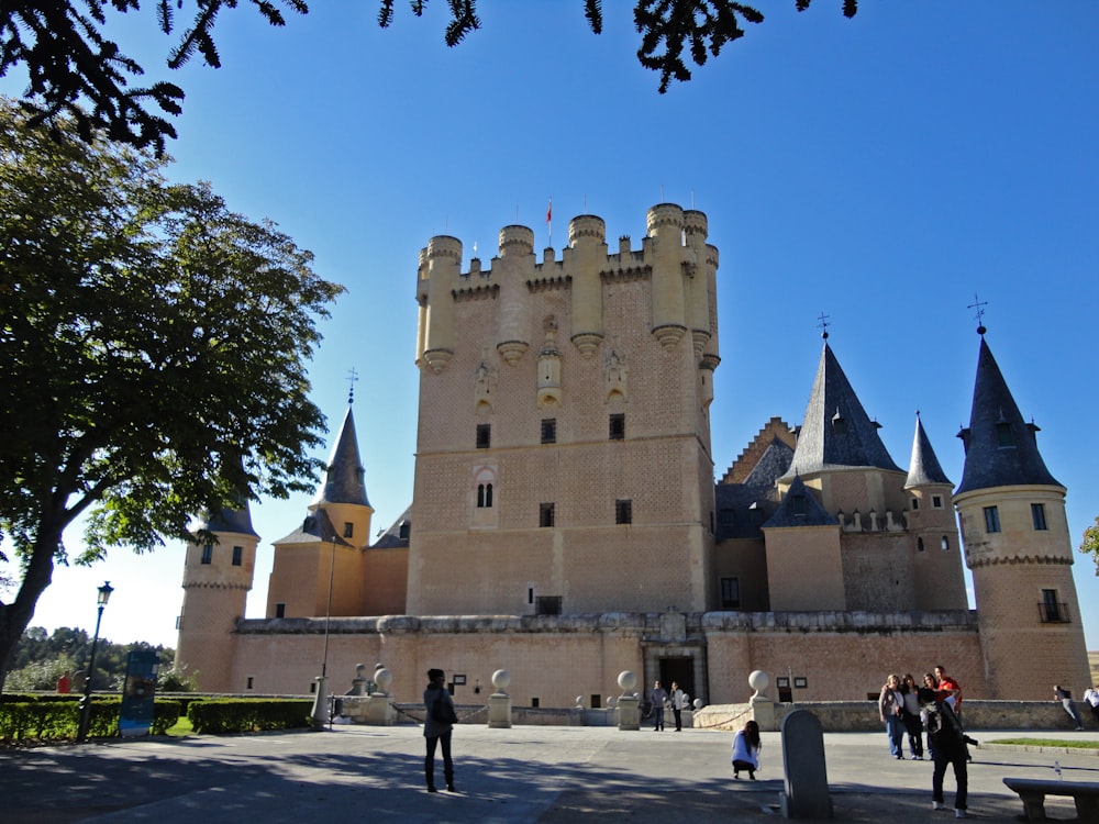 a castle with people walking around with Alcázar of Segovia in the background