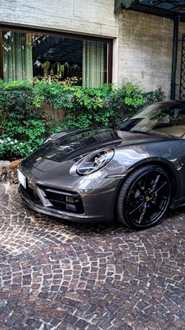 White Porsche with gleaming rims and mirror-like finish in a modern driveway.