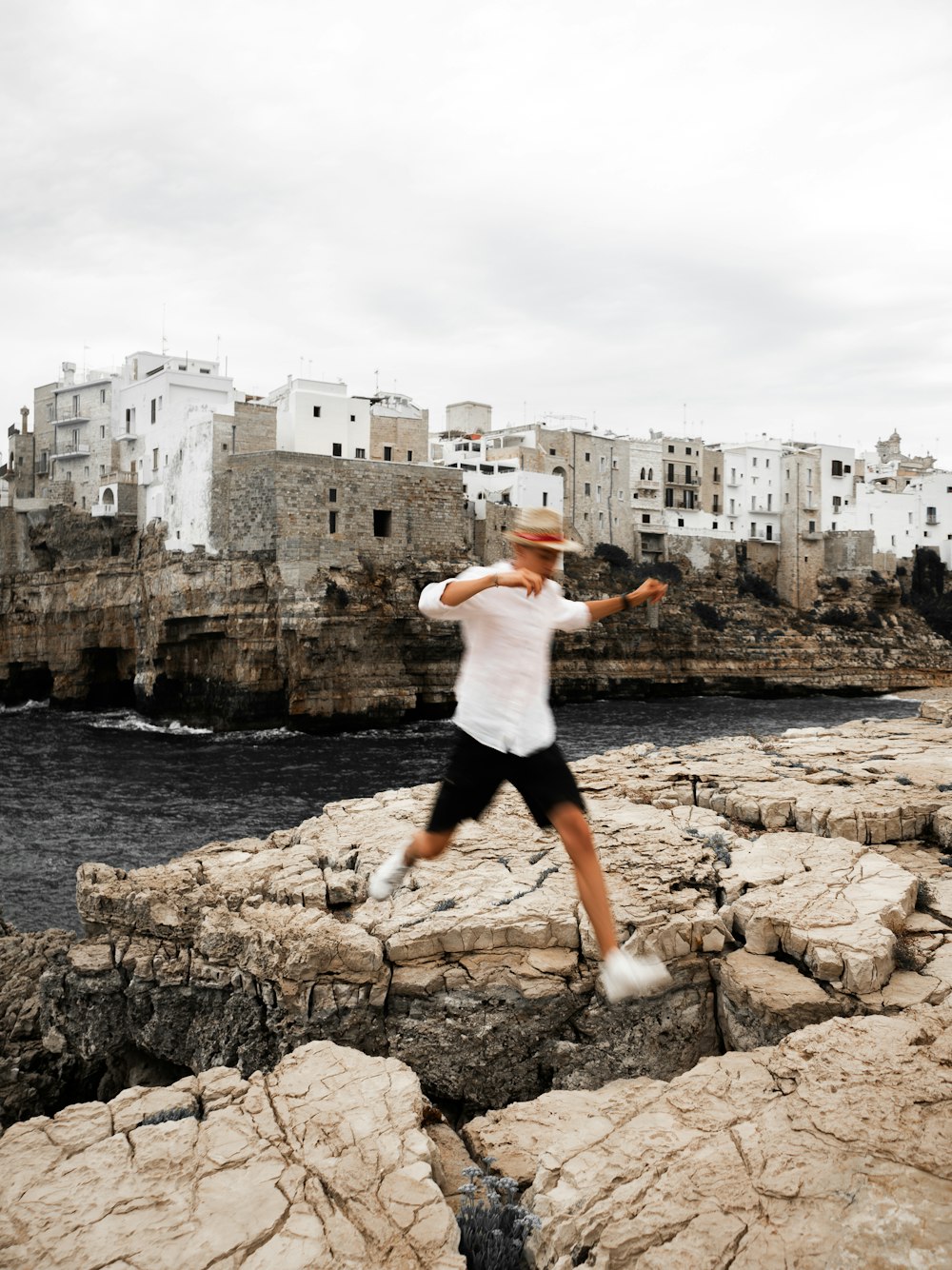 a man jumping on a rocky beach