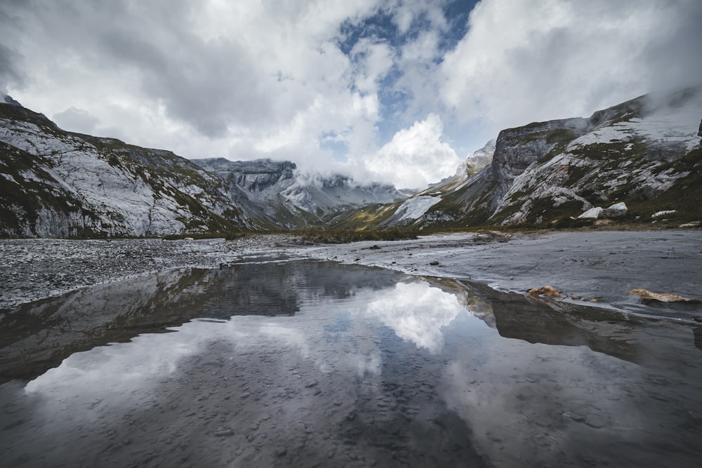 a rocky beach with snow and mountains