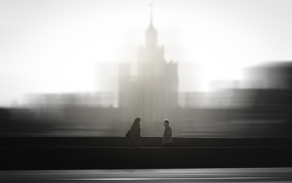 a man and a woman sitting on a bench in front of a large building