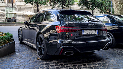 Wide stance of an Audi RS model featuring sharp side skirts and fender flares in a dark, urban environment.