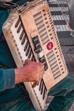Hands rewaxing reed blocks on an accordion with tools nearby.