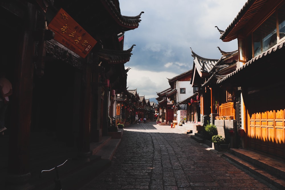 a cobblestone street lined with buildings and a cloudy sky