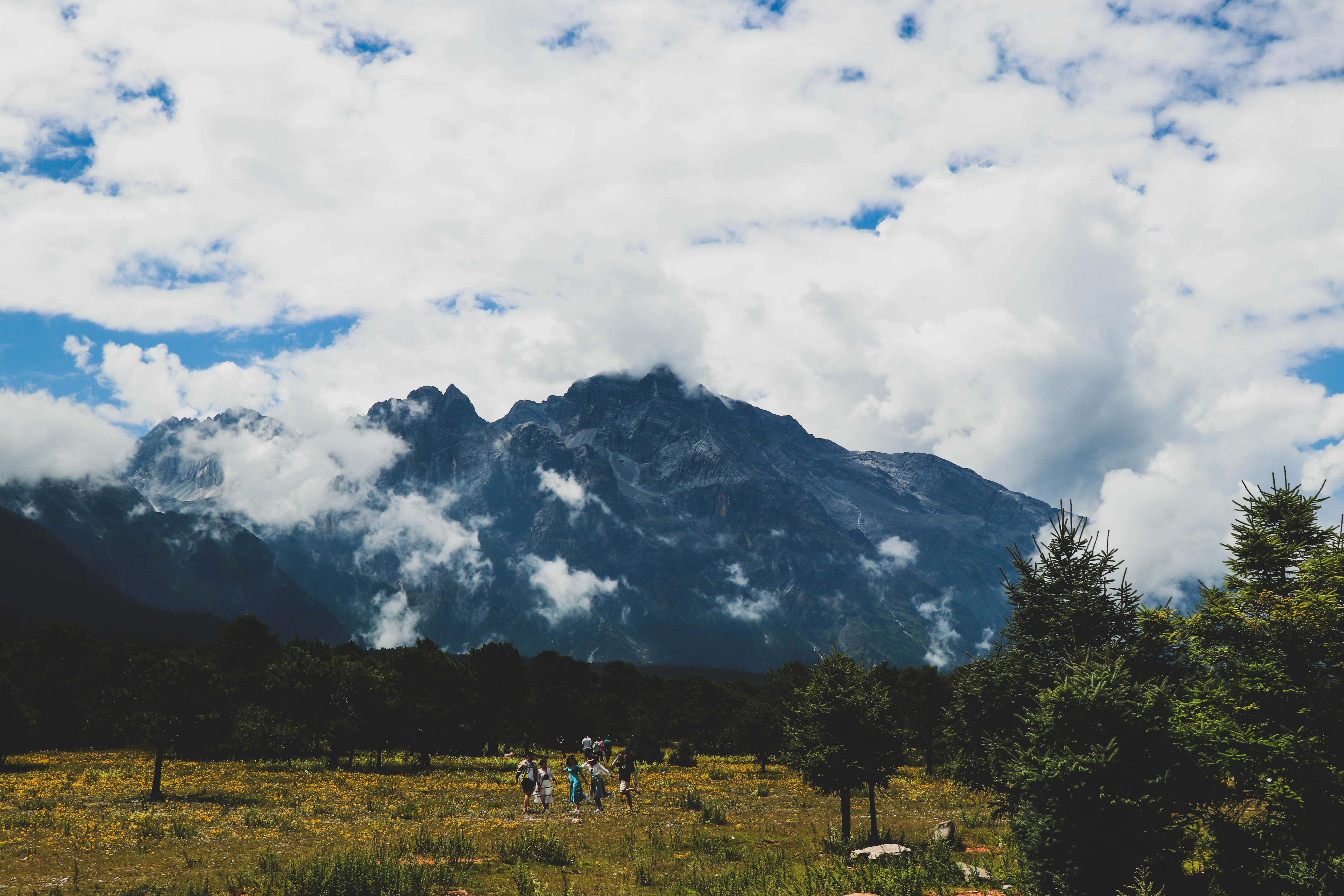 a group of people walking on a trail in front of a mountain