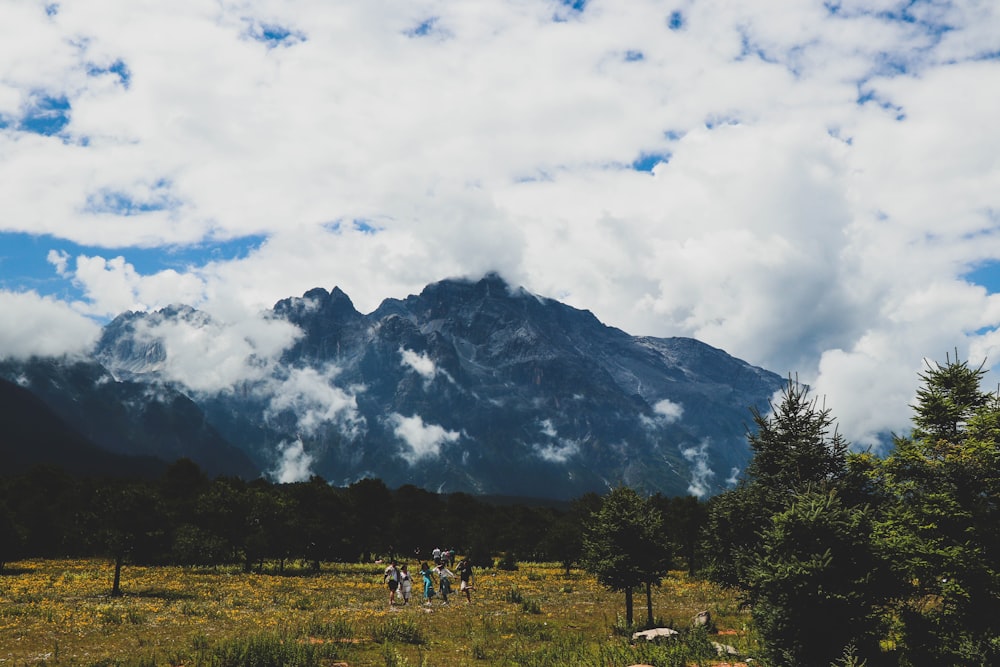 a group of people walking on a trail in front of a mountain