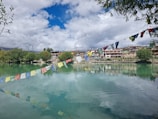 A tranquil temple pond reflecting ornate pillars and fluttering prayer flags.