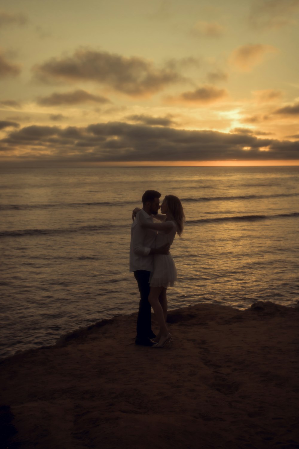 a man and woman kissing on a beach