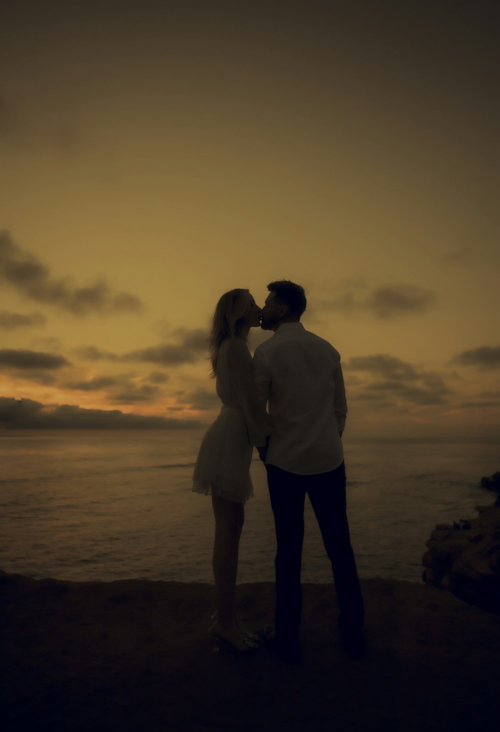 a man and woman kissing on a beach