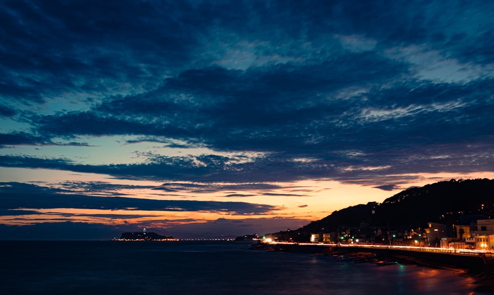 a body of water with buildings and mountains in the background