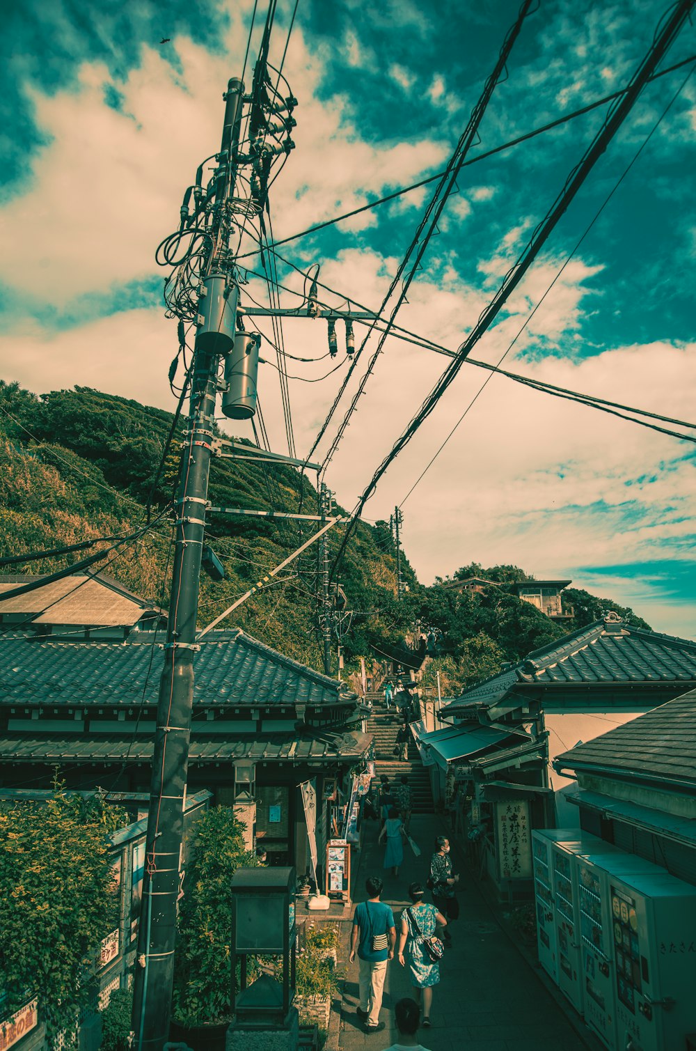 a group of people walking on a street with buildings and wires above