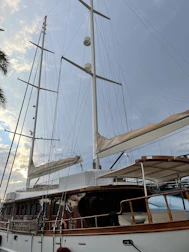 A sailing yacht under construction showing wooden masts and sails being fitted.