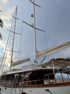 A sailing yacht under construction showing wooden masts and sails being fitted.