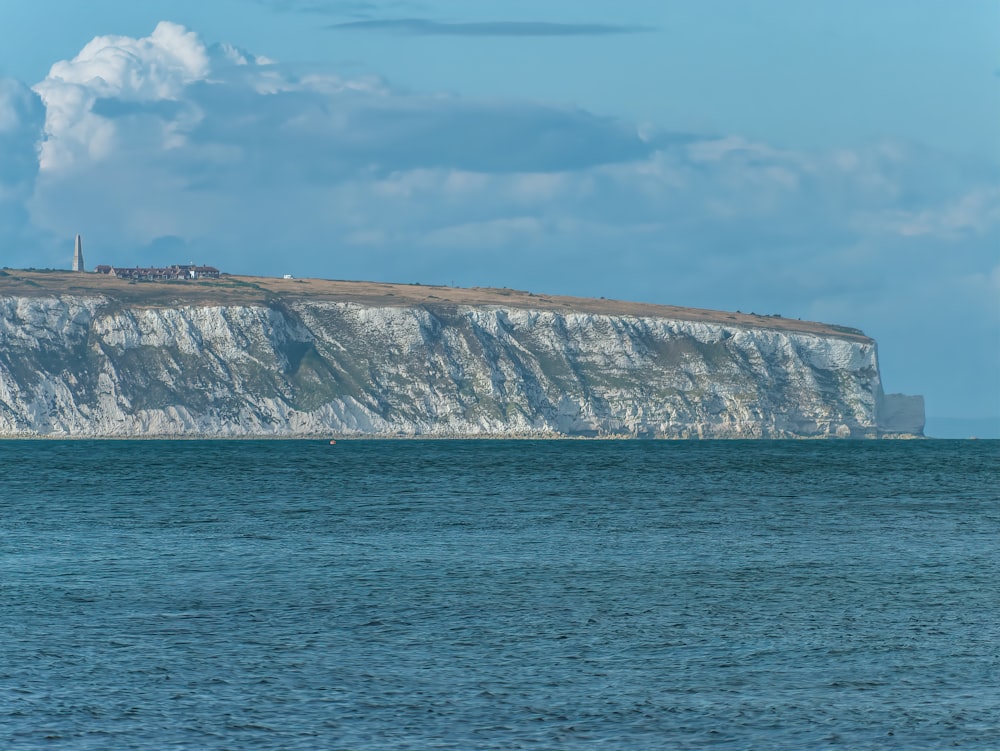 a large cliff next to a body of water with White Cliffs of Dover in the background