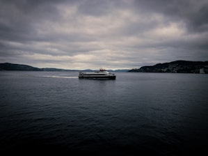 A small passenger ferry crossing the waters around Chiloé island under a cloudy sky.