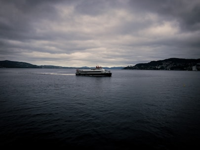 A small passenger ferry crossing the waters around Chiloé island under a cloudy sky.