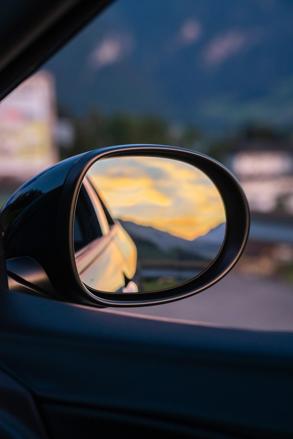 a side view mirror showing a yellow sunset
