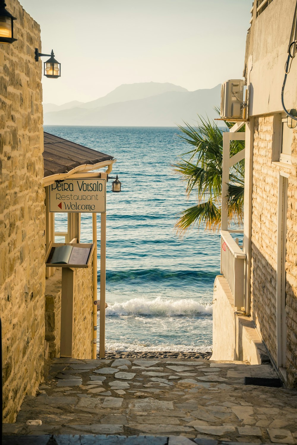 a stone path with a sign on it next to a body of water