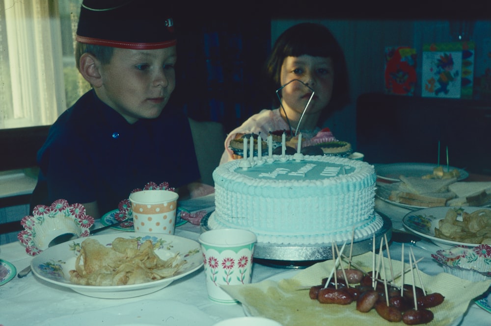 a couple of people sit near a cake