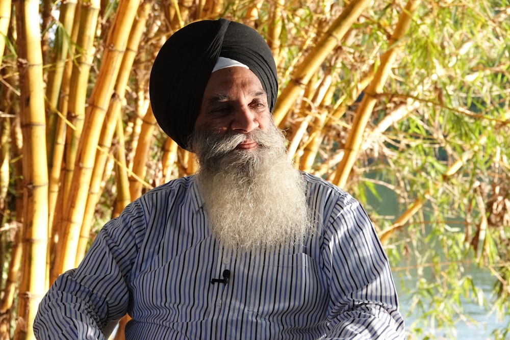 a man with a beard and a hat in front of trees