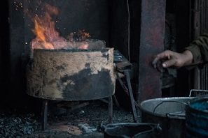 A hand holding a titanium seed plate against a backdrop of glowing embers, demonstrating its heat resistance.