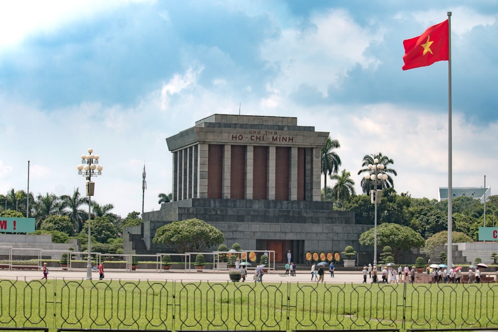 a large building with a flag in front of it with Ho Chi Minh Mausoleum in the background