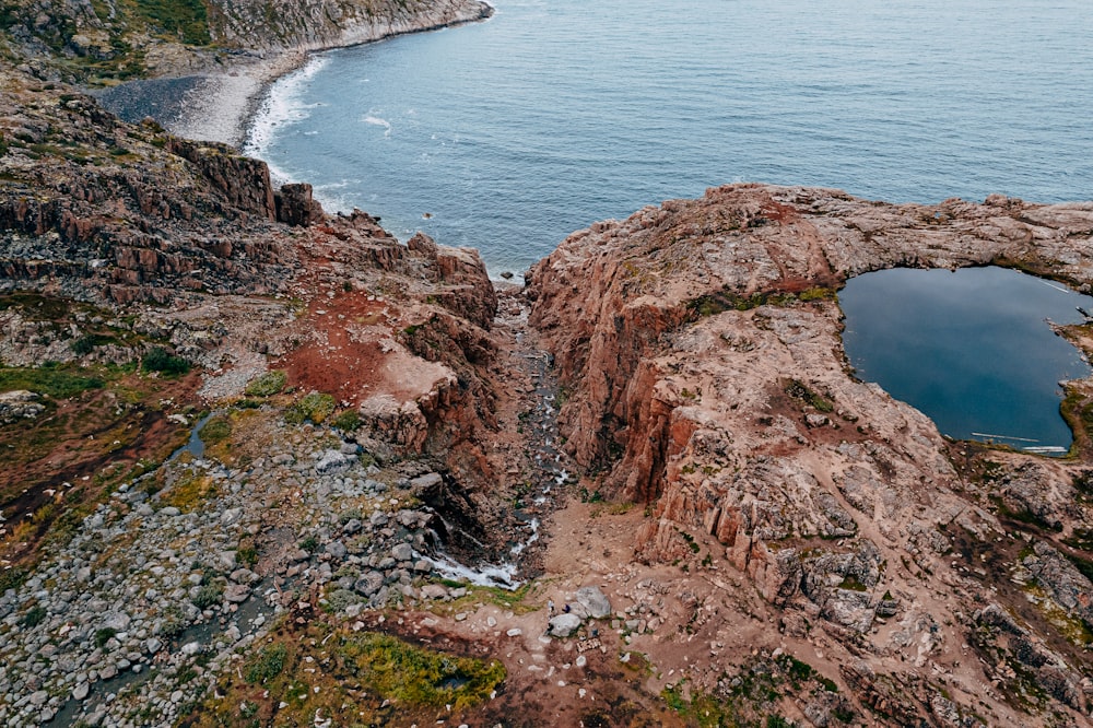 a rocky cliff next to a body of water