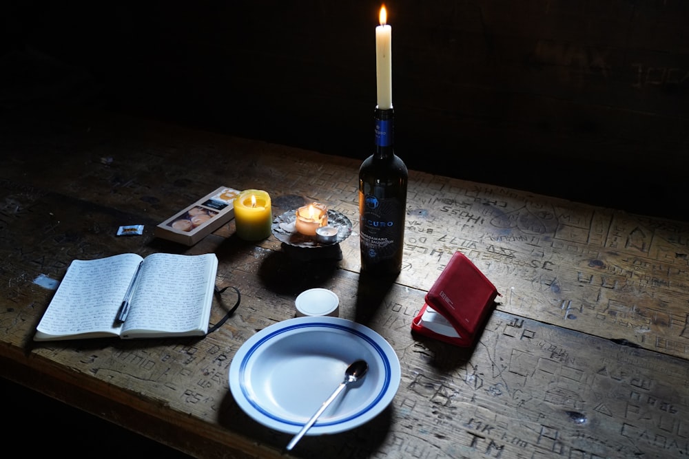 a table with a bottle and a plate of food and a candle