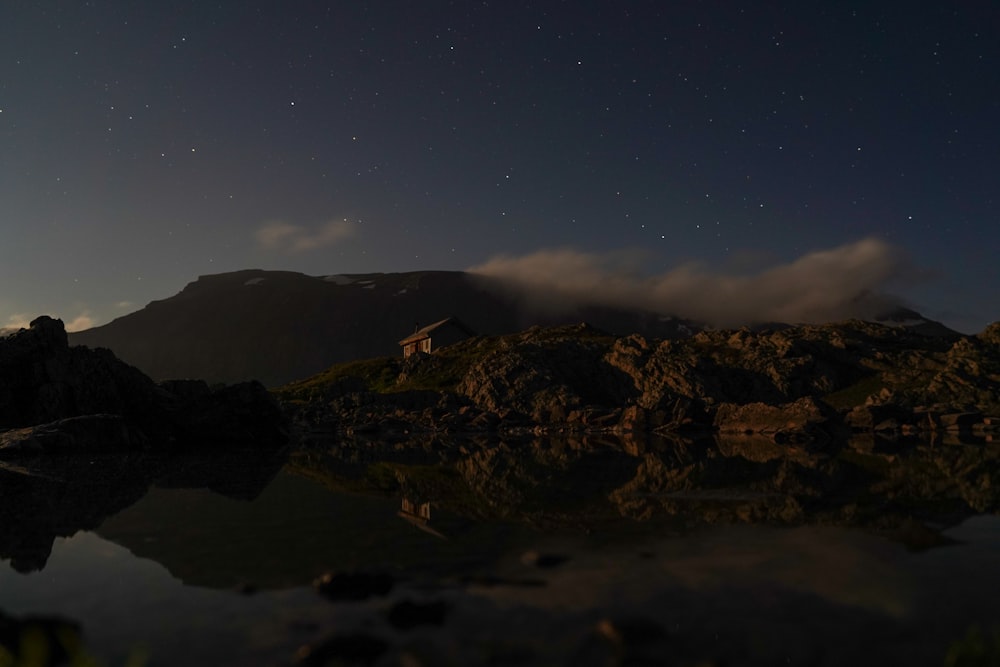 a body of water with a rocky shore and a mountain in the background