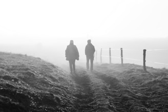 two people walking on a dirt path