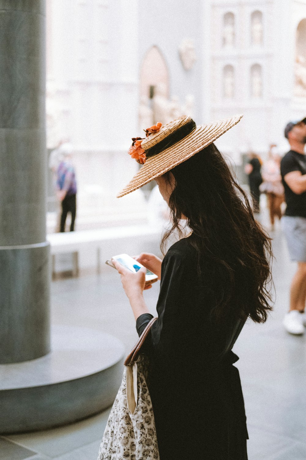 Eine Frau mit Hut und Handy in der Hand
