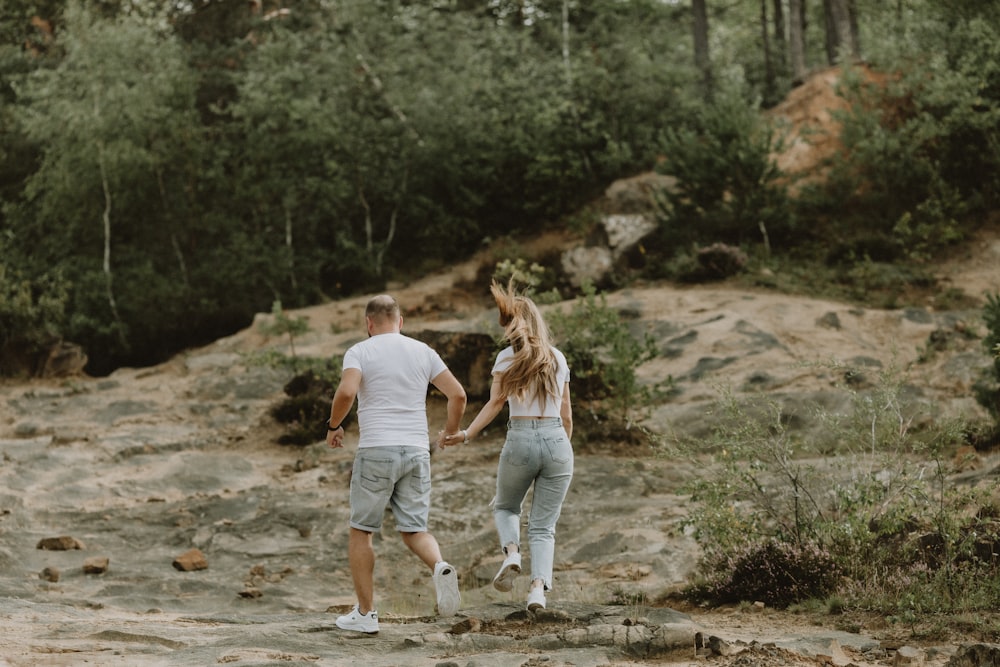 a man and woman walking on a dirt path in the woods