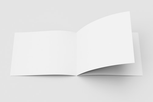 An open blank book is displayed on a plain surface. The background is minimalist and white, accentuating the simplicity and cleanliness of the scene.