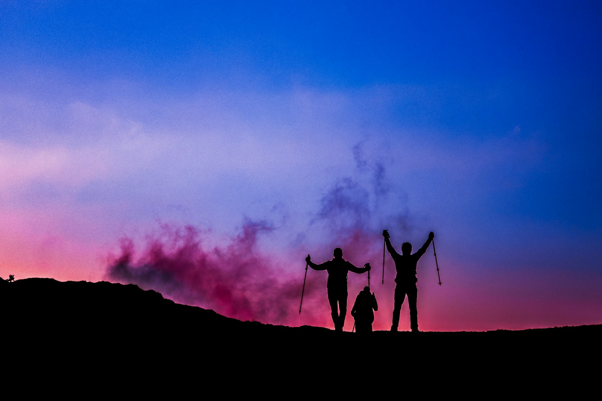 a group of people standing on a hill with their arms raised