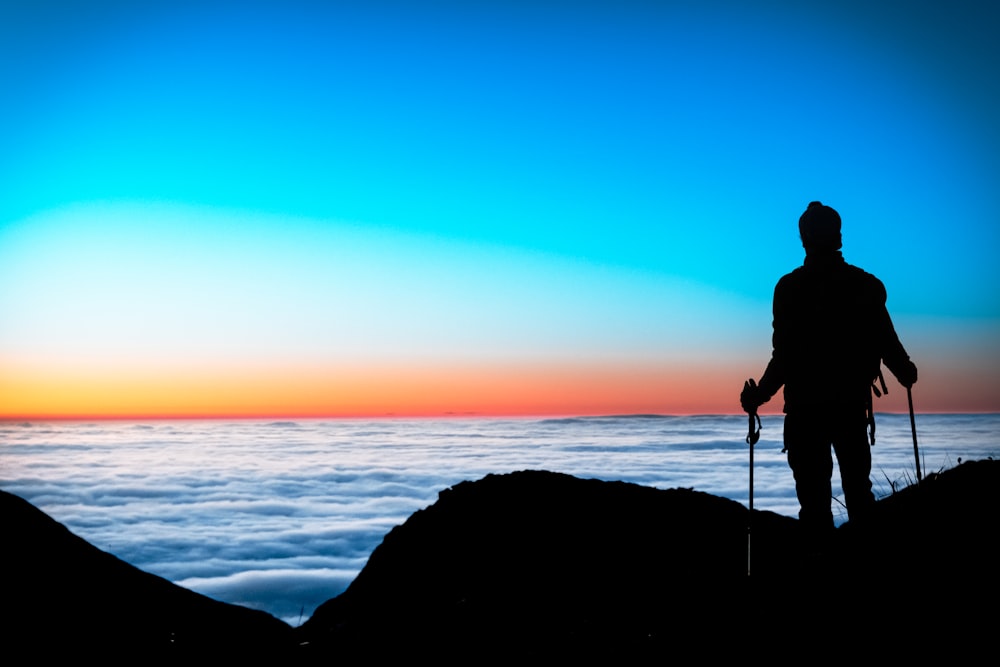 a person standing on a cliff looking at the sunset