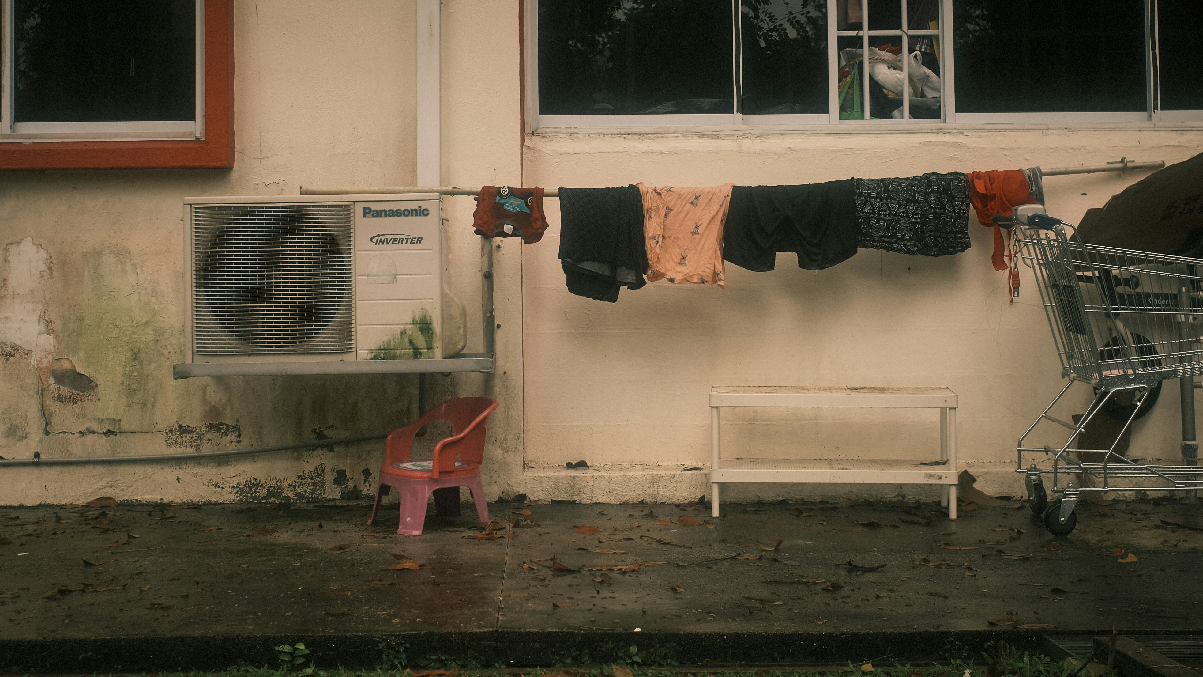 a red chair next to a white building with clothes outside