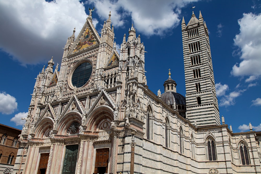 un grande edificio con torri con il Duomo di Siena sullo sfondo
