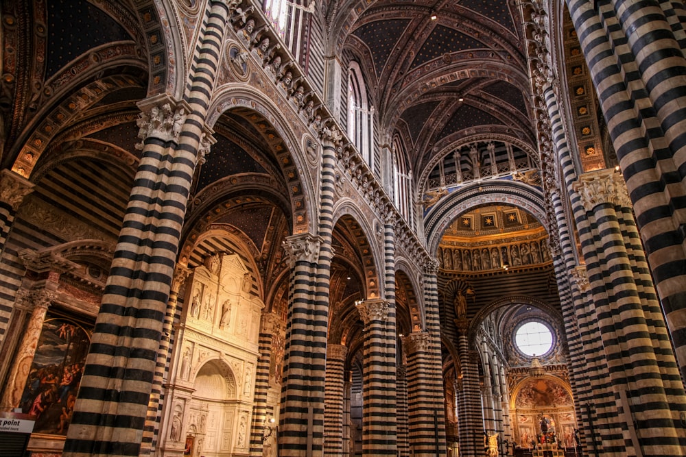 ein großes reich verziertes Gebäude mit vielen Bögen mit dem Dom von Siena im Hintergrund