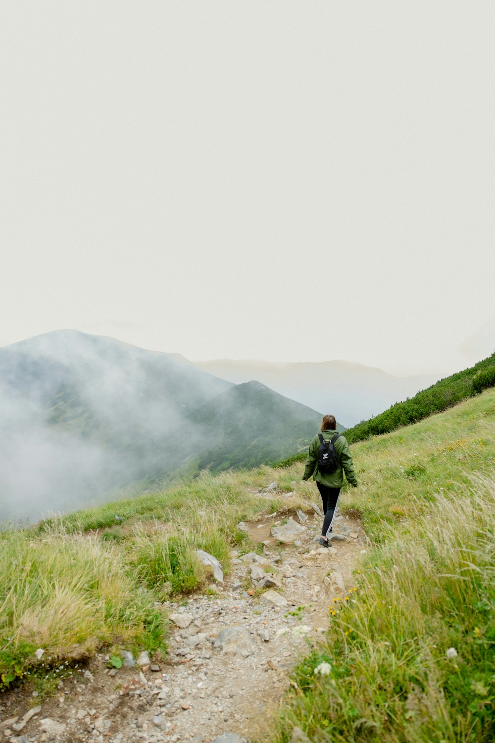 a man walking on a trail in a foggy valley