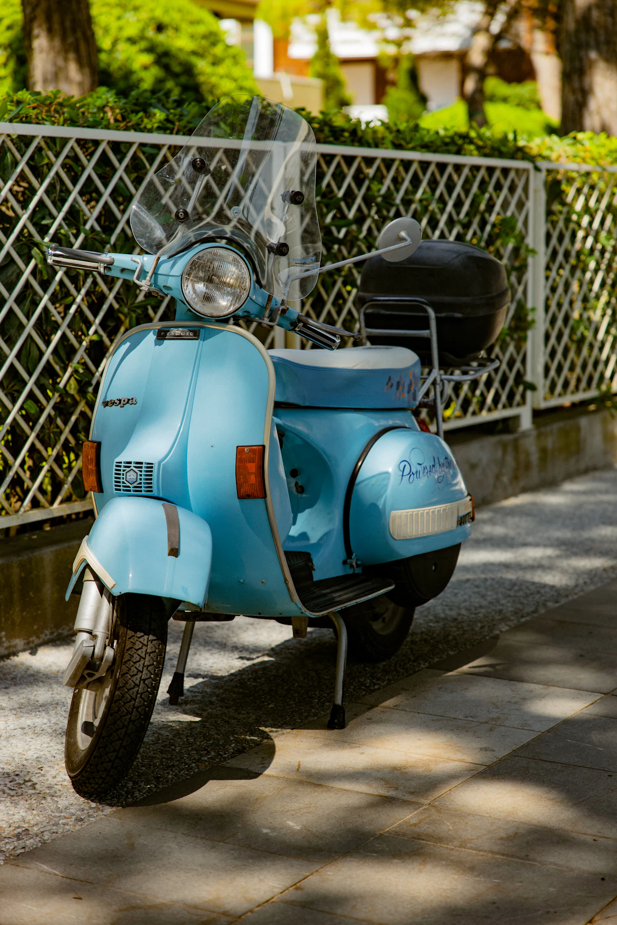 Skuter biru terparkir di trotoar