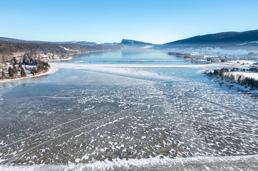 a snowy landscape with a body of water and mountains in the background