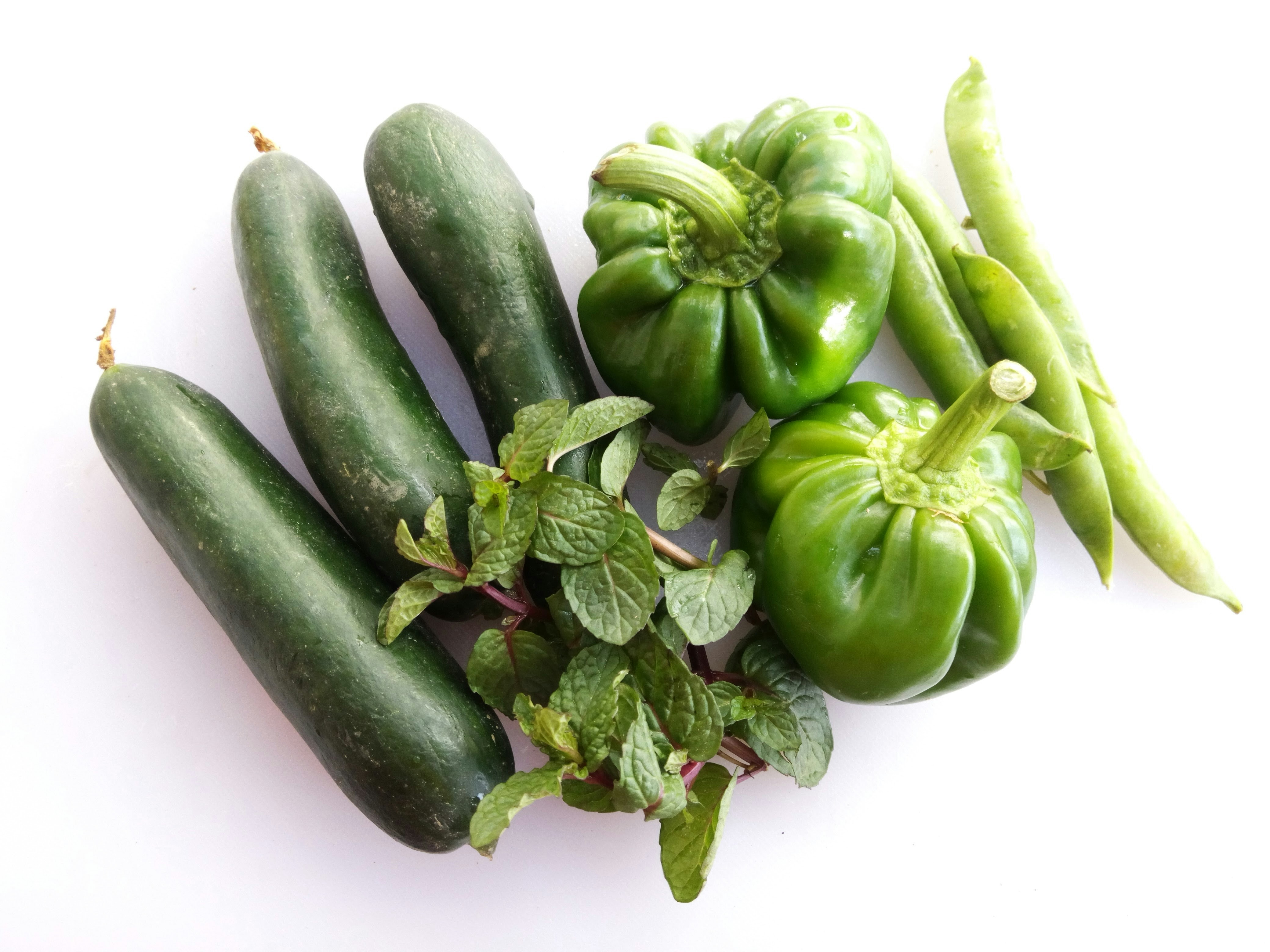 Colorful fresh vegetables including broccoli, peppers, and tomatoes on a bright white surface