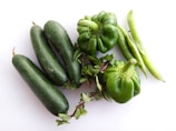 Fresh cucumbers and bell peppers arranged neatly on a wooden table.