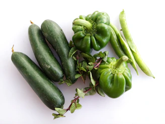 Close-up of crisp, green vegetables like lettuce, cucumbers, and bell peppers stacked neatly.