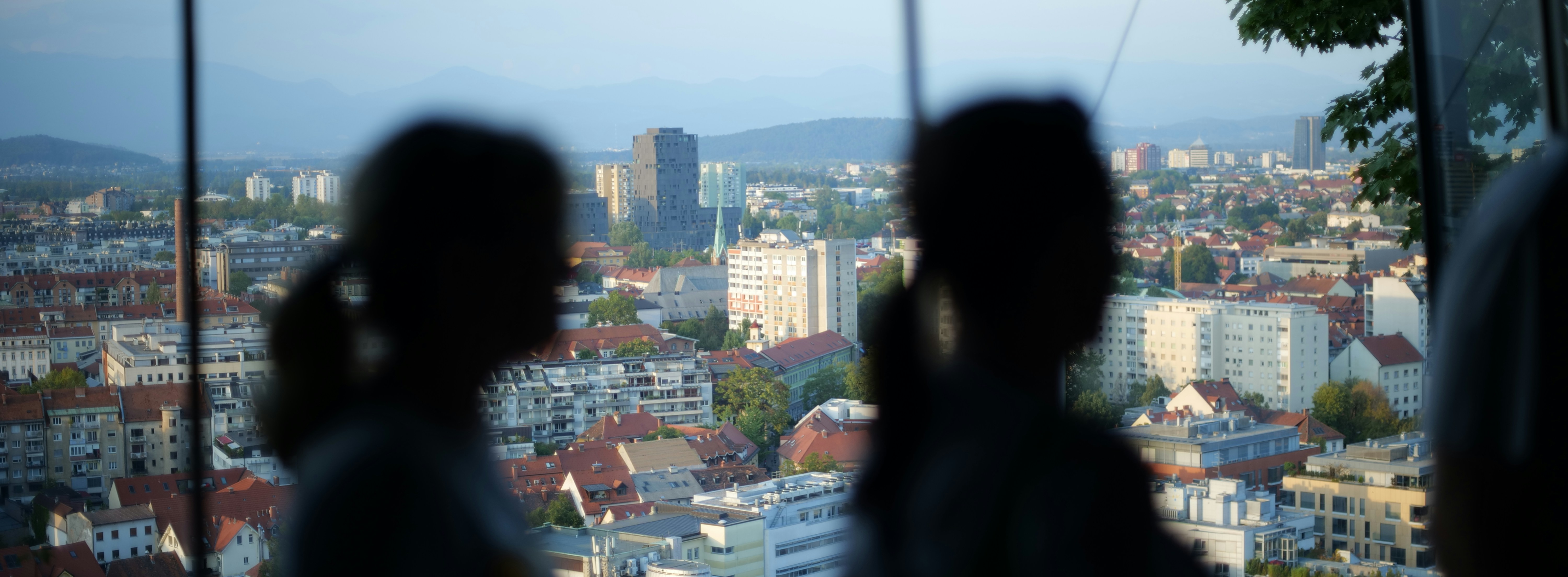 a couple of people looking out a window at a city